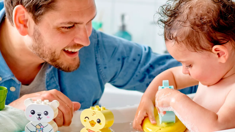 Um pai brincando com seu filho no banho.