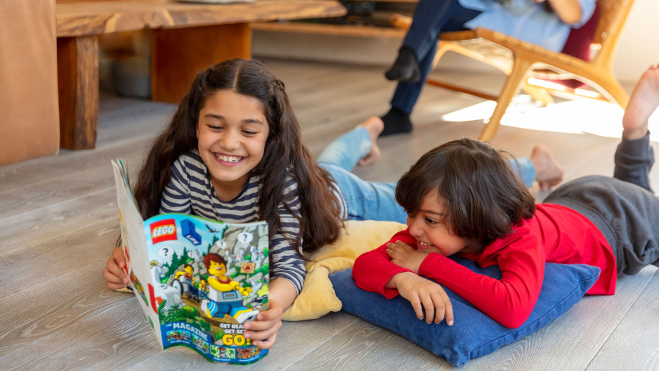 Duas crianças lendo uma revista lego.