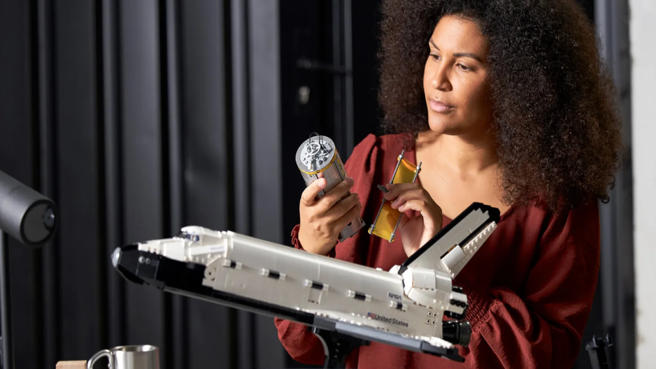 Image of a woman holding tools and behind a lego spaceship